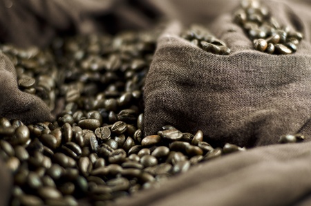 Grains of black roasted coffee on brown clothの写真素材