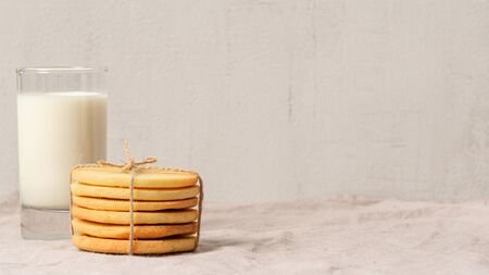Stack of homemade cookies twisted with a rope on a grey background. Glass of milk. Close up. Macro photo. Copy space. Healthy snack for kids.の写真素材