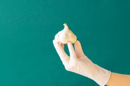 White rubber gloved hand holding garlic. Coronavirus. Copy space.の写真素材