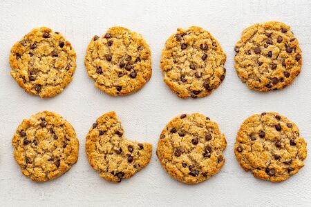 Chocolate chips crunchy cookies, biscuit on a table. One cookie bitten. Top view. Banner Grey background. Snack, breakfast, fast food. Sweet tasty dessert. Isolated. Close up. Bakery conceptの写真素材