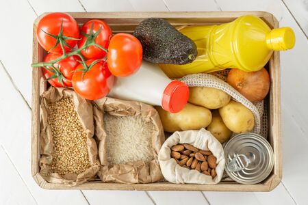 Food donation wooden box with vegetables, fruits, pasta, groats, oil, milk and canned food. Top viewの写真素材