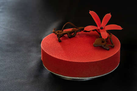 Red birthday cake with chocolate flower isolated on a black background. Copy space. Close up. High quality photoの写真素材