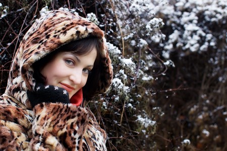 Young woman in leopard fur coat smiling with snowの写真素材
