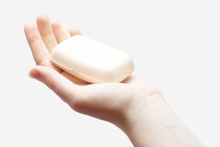 Hand holding piece of creamy soap on whiteの写真素材