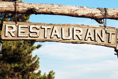 Restaurant signboard with carved wooden letters and skyの写真素材