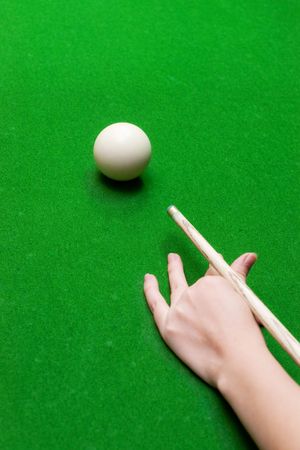 Closeup of female hand with billiard cue ready to hit white ball with selective focusの写真素材