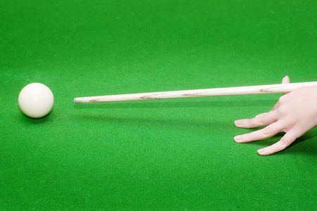 Closeup of female hand with billiard cue ready to hit white ball with selective focus and vignetting...