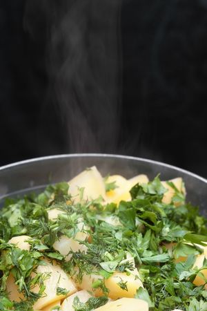 Hot boiled potatoes with cut dill and parsley with smoke and selective focusの写真素材