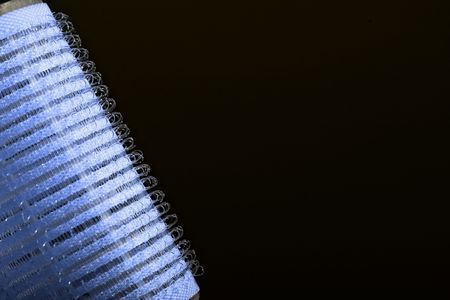 Blue hair curler against black background の写真素材