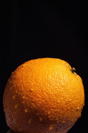 Part of orange with water drops isolated against black background with selective focusの写真素材