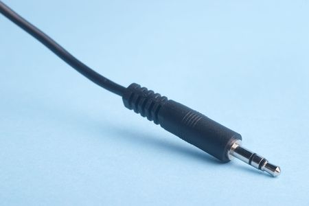 Closeup of audio mini jack plug on blue background with selective focus