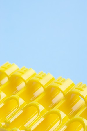 Empty slots of yellow battery storage container against blue background with selective focusの写真素材