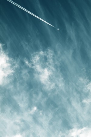 Airplane contrail against sky with diffused white clouds with copy spaceの写真素材