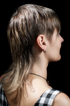 Boyish short haircut of a young woman viewed from side against dark background の写真素材