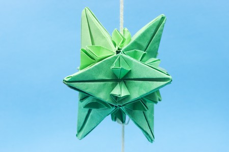 Closeup of abstract shaped green paper origami objects on thread with selective focus on the top oneの写真素材