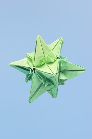 Closeup of abstract shaped green paper origami isolated against blue background with selective focusの写真素材