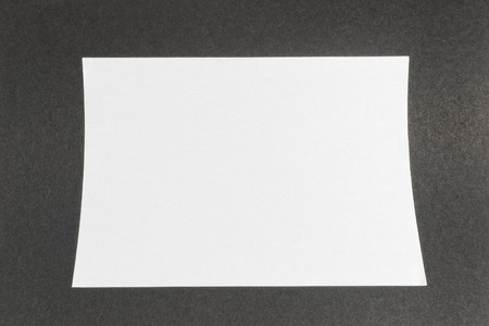 white a4 sized paper on black textured backgroundの写真素材
