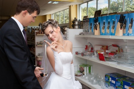 Groom and bride holding soup ladle in kitchen utensils section of a storeの写真素材