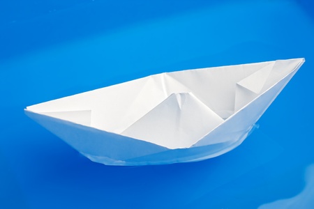 closeup of folded paper ship on blue water with selective focus の写真素材