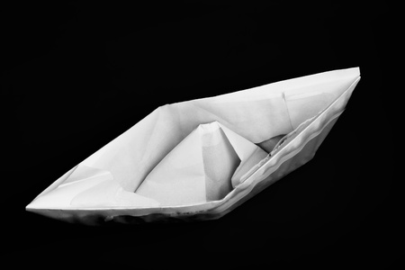 Closeup of sinking folded paper ship against black background with selective focus の写真素材