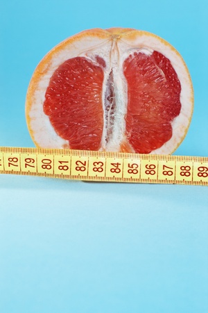 Cut half of juicy grapefruit with centimeter on blue background with copy spaceの写真素材