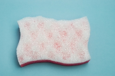 White porous bath sponge in shape of flag on blue paper backgroundの写真素材