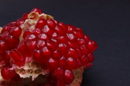Closeup of piece of pomegranate on black with selective focus and copy spaceの写真素材