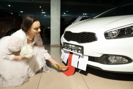 bride in white dress feeding a car with carrotの写真素材