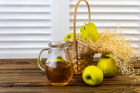 Green apples, basket with apples and jug with apple juice on wooden backgroundの写真素材