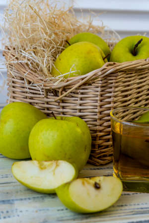 Green apples, glass with apple juice and basket with apples on wooden backgroundの写真素材