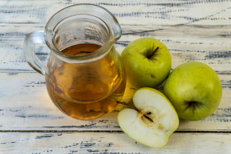 Green apples and jug with apple juice on wooden backgroundの写真素材