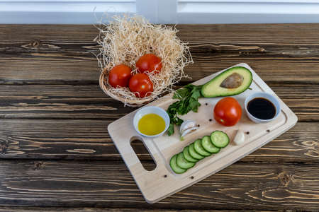 Tomatoes, cucumbers and avocado on the table, olive oil and balsamic vinegar, garlic, vegetables, vegetarianism, healthy eatingの写真素材
