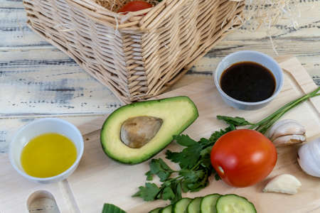 Vegetables on the table and in a basket, tomatoes, cucumbers, avocado, garlic and olive oil,...
