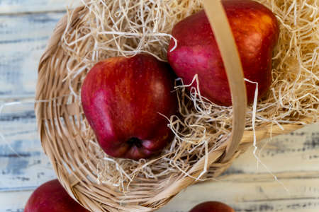 Red apples in a basket and on a wooden tableの写真素材
