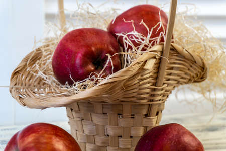 Red apples in a basket and on a wooden tableの写真素材