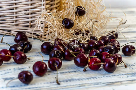 Cherry and cherry juice or wine on a wooden table, a decanter and a glass with juice, a basket with cherriesの写真素材