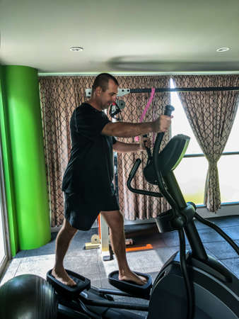 Man is engaged in sports, makes exercises on simulators in the gym