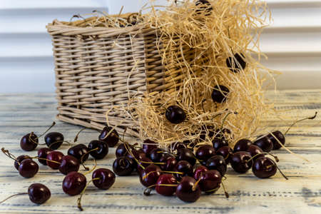 Cherry and cherry juice or wine on a wooden table, a decanter and a glass with juice, a basket with cherriesの写真素材