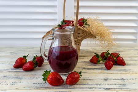 Strawberry in basket and on table on wooden background, strawberry juice in jugの写真素材