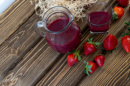 Strawberry in basket and on table on wooden background, strawberry juice in jugの写真素材