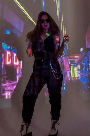 silhouette of a young beautiful woman on the background of neon projector inscriptions, slight blur