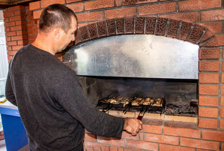 man doing barbecue, grilling kebabs on the fire in the oven