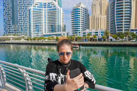 young beautiful woman walking along Dubai Marina in Dubai, UAE,
