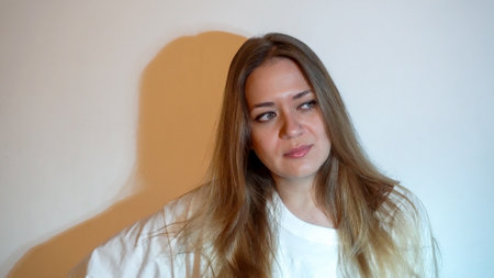 Young beautiful woman with long hair and green eyes. wearing a white t-shirt with a tattoo on her...
