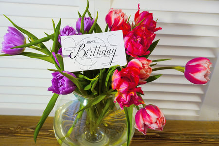 postcard , Internet banner with a birthday greeting, with the inscription - happy birthday, a bouquet of flowers with a note of congratulations, tulipsの写真素材
