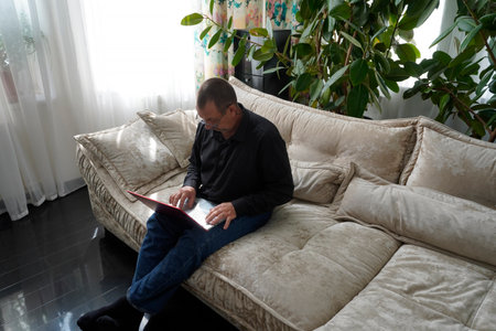man sitting on sofa and working on laptopの写真素材