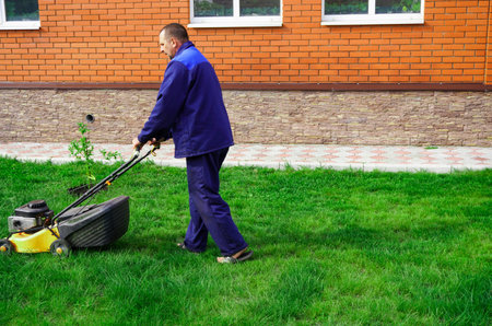 The man is working in the garden. Mowing grass with a lawn mower.の写真素材