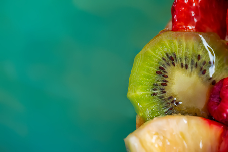 Slice kiwi and a variety of fresh fruits in sweet gelatin. Berries close-up in soft focus. Delicious dessert. Beautiful background of fruit. Food. Top view. Copy space. Macro.の写真素材