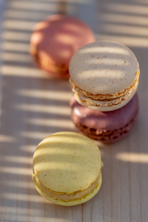 Delicious sweet airy French pastries on a rustic table. Dessert macarons in the summer evening in the orchard. Sunlight. Natural blurred background. Image in soft focus, bokeh and close-upの写真素材