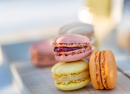 French macarons in the summer evening in the garden. Delicious sweet airy colored french pastries. Natural blurred background. Image in soft focus close-up.の写真素材